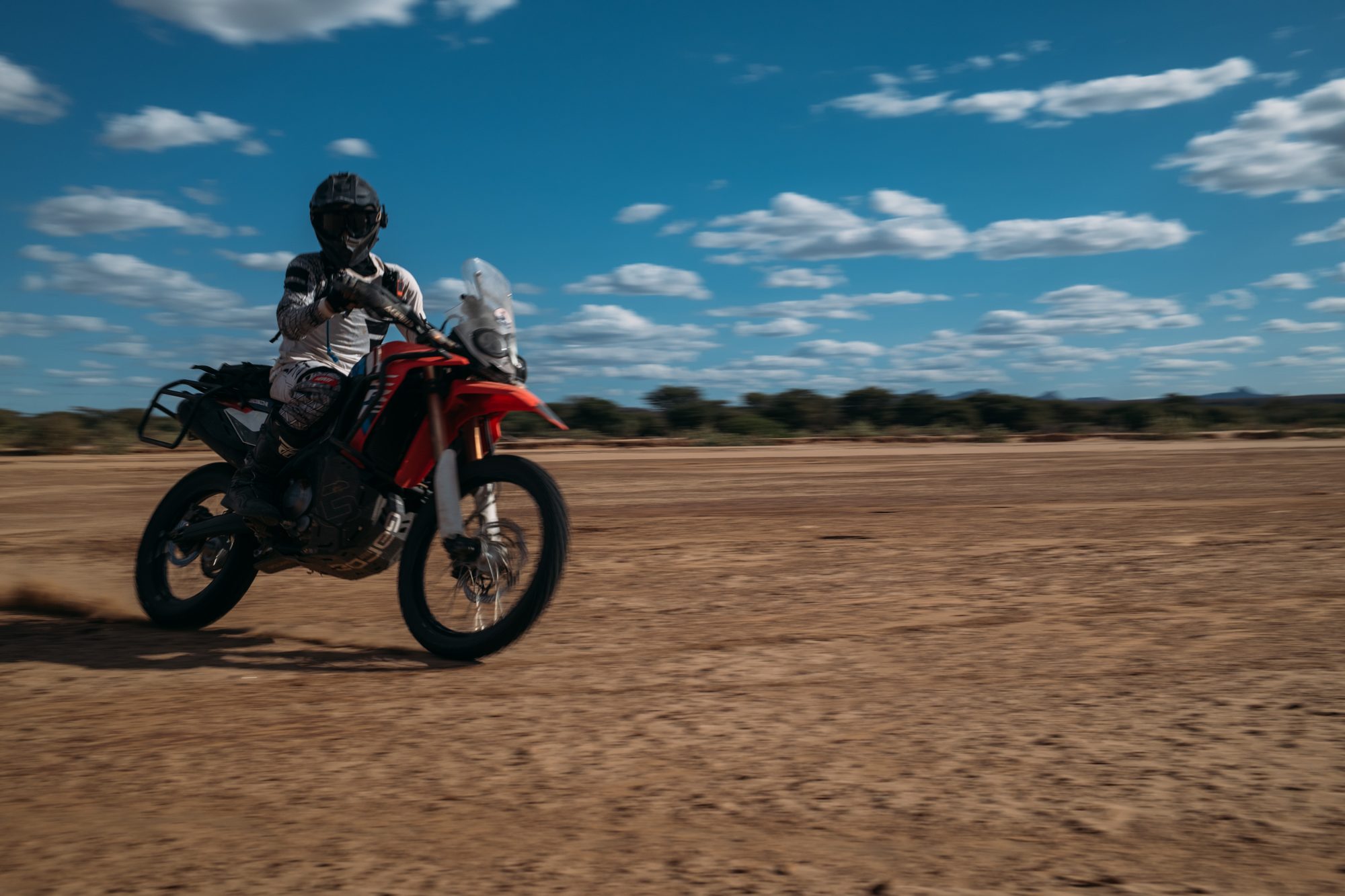 A rider on a Honda CRF300 Rally on a wide dry riverbed