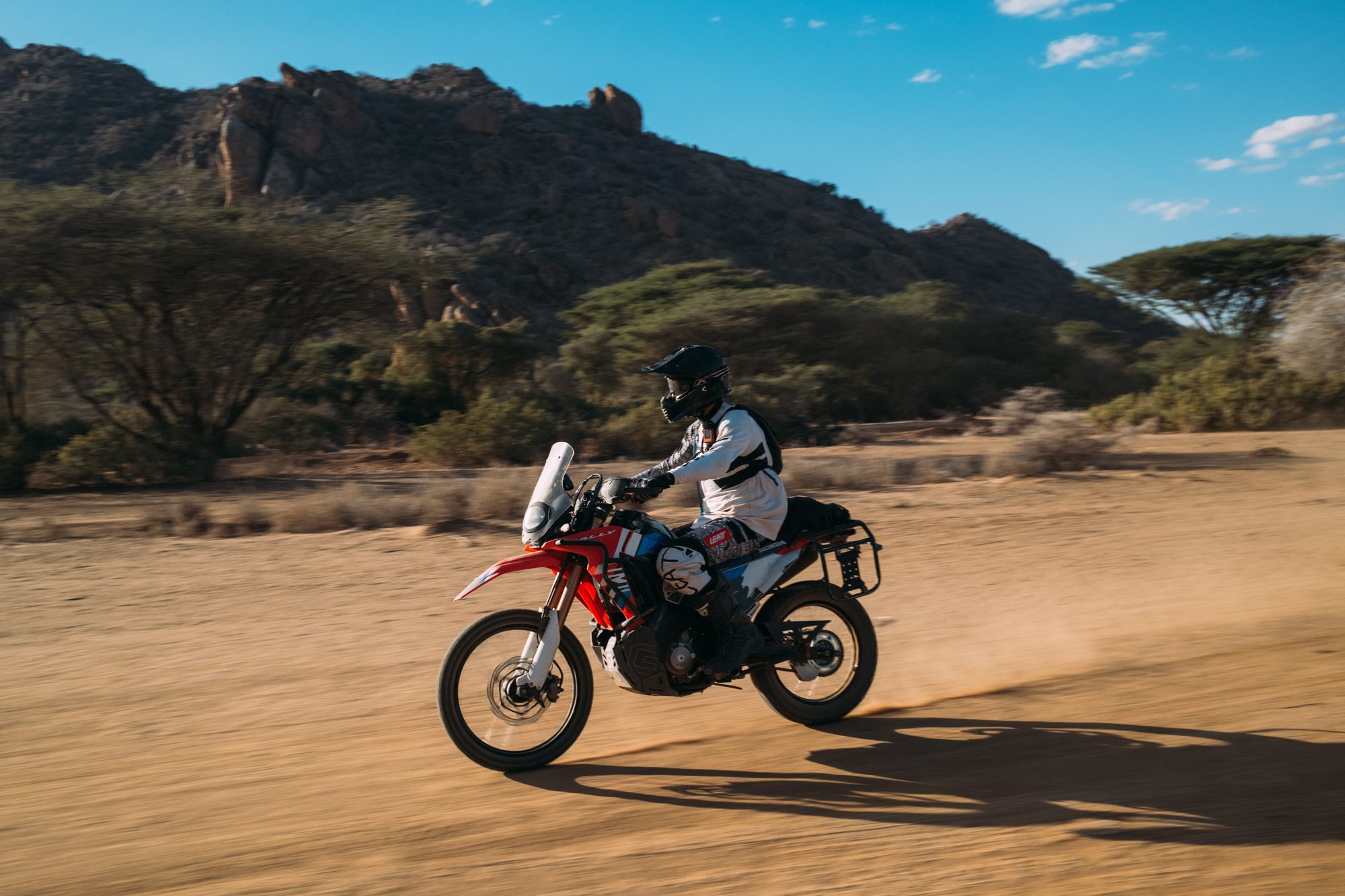 A rider on a red Honda in acacia country
