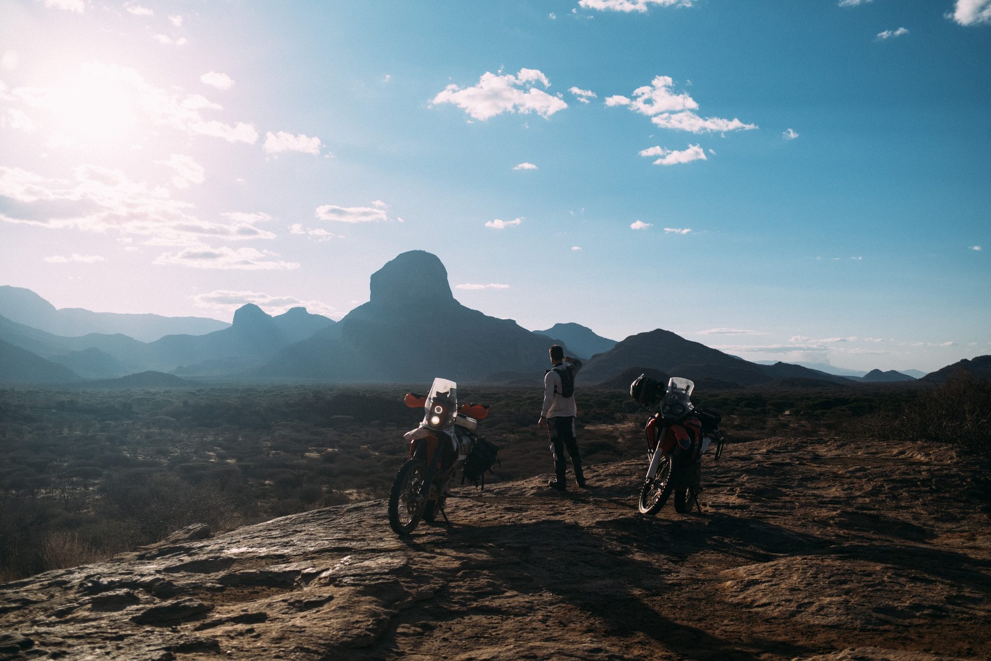 Riders on a rocky ridge at sunset, a peak in the distance