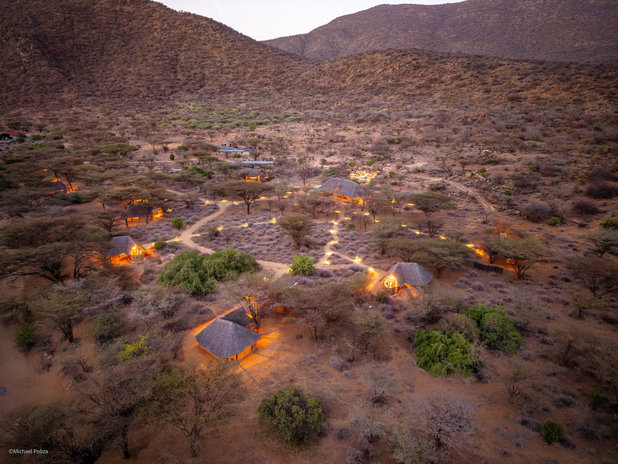 Koros Camp from above at dusk, lamps lit among the bush
