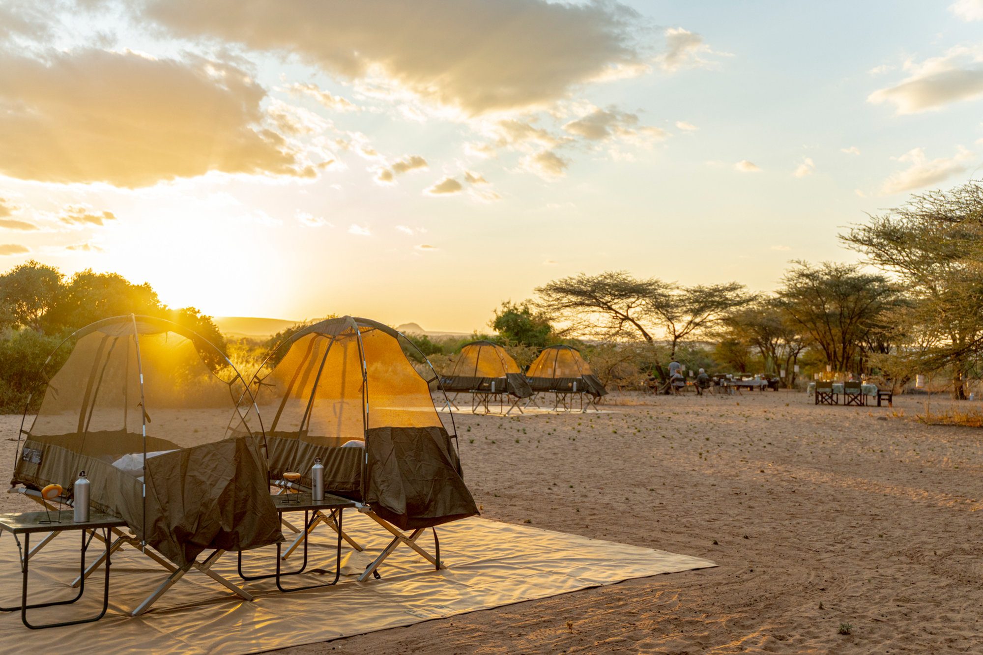 A tent and camp table set up on open ground at sunset in northern Kenya