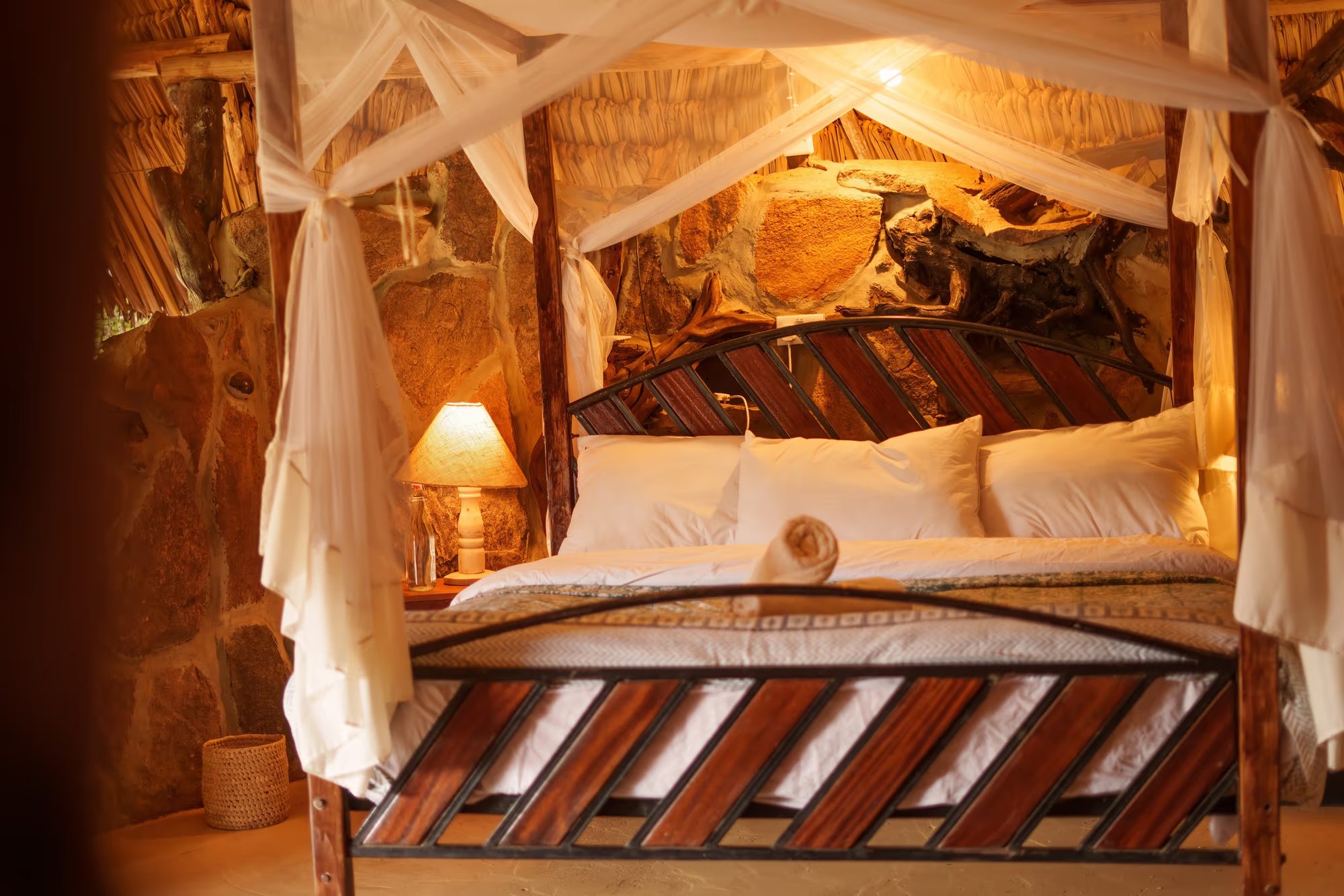 A four-poster bed under thatch in a banda at Ol Gaboli