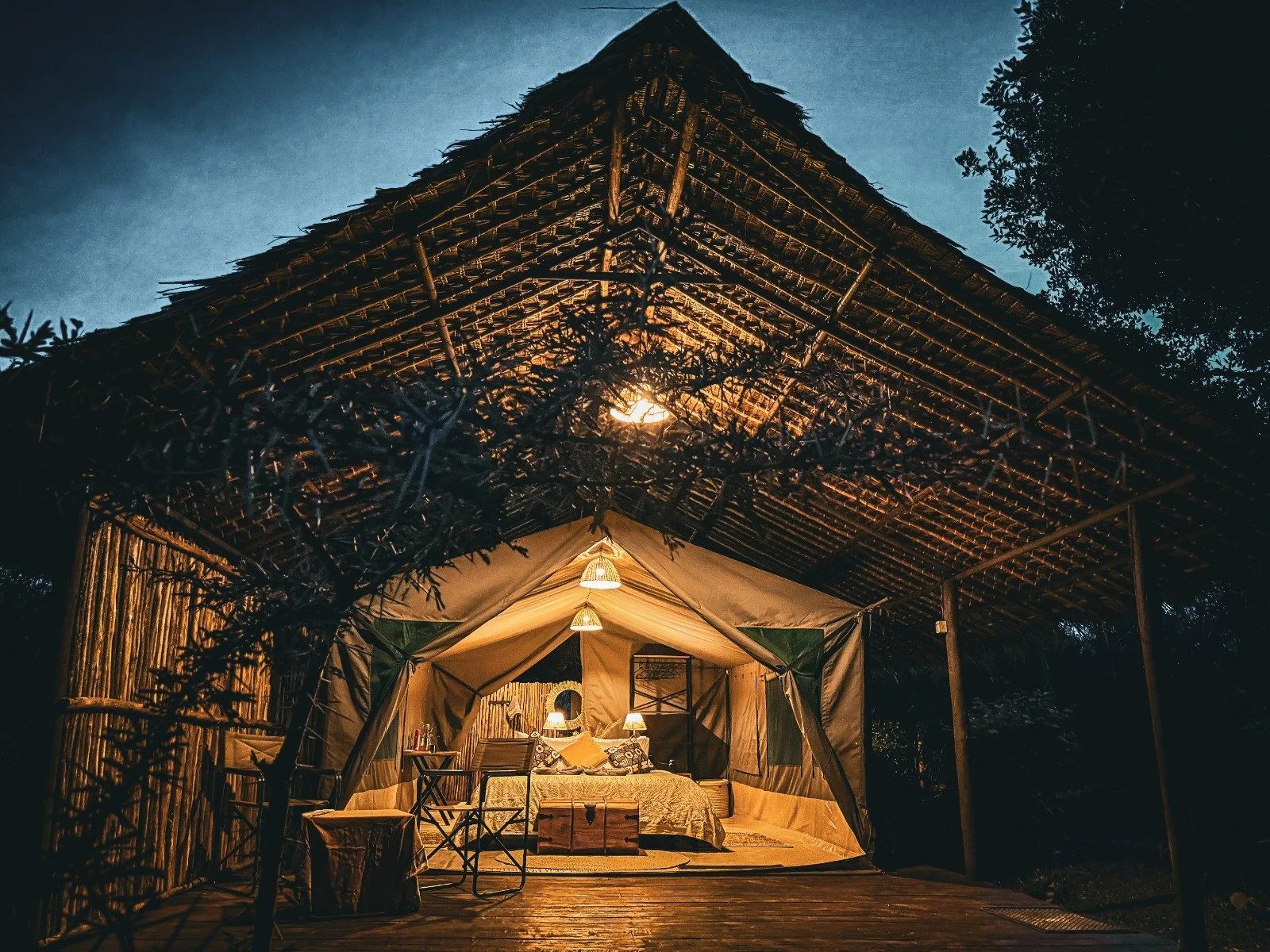 A raised safari tent at Amazing Laikipia Camp, lamps lit at dusk
